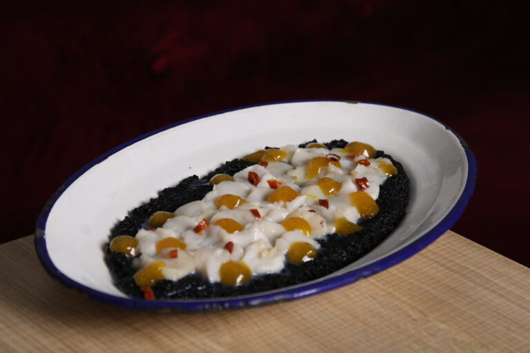 Tiradito de vieira con cous cous negro, chile de árbol y mango